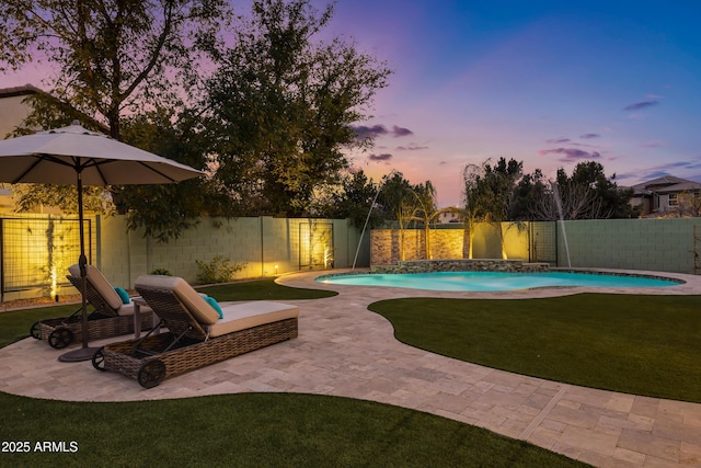 pool at dusk with a yard, a patio area, and pool water feature