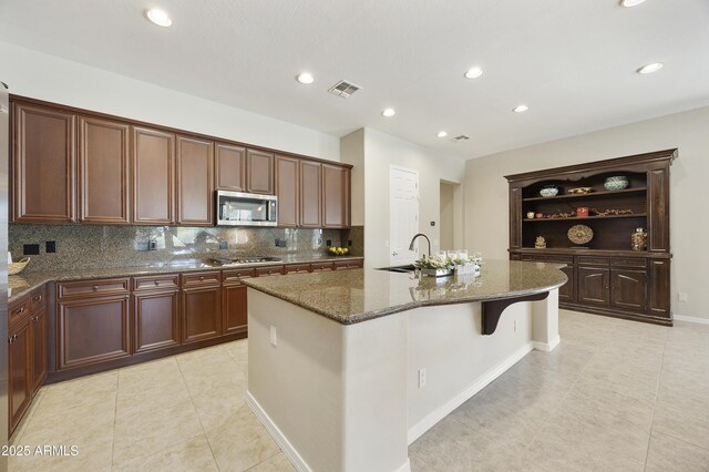 2727 S Balboa Dr, Gilbert, AZ 85295 - kitchen featuring stainless steel appliances, open shelves, light tile patterned flooring, an island with sink, and dark stone countertops