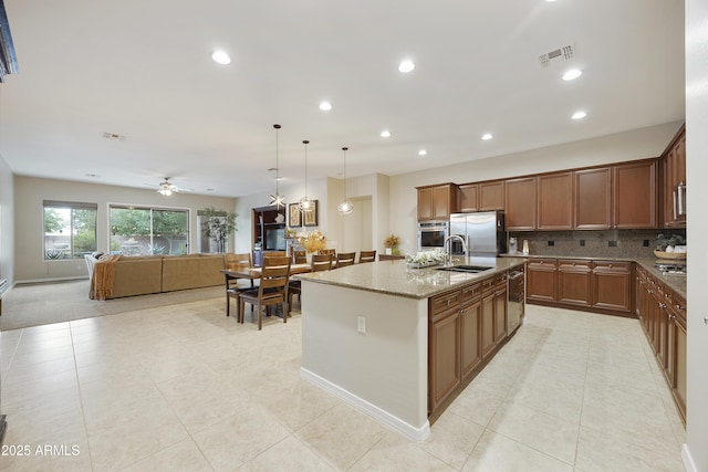 2727 S Balboa Dr, Gilbert, AZ 85295 - kitchen featuring appliances with stainless steel finishes, a sink, light stone counters, decorative backsplash, and a kitchen island with sink