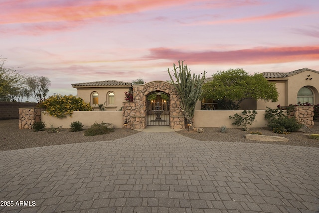 2727 S Balboa Dr, Gilbert, AZ 85295 - mediterranean / spanish-style home featuring a gate, a fenced front yard, stucco siding, and decorative driveway