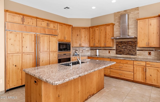 kitchen featuring backsplash, a sink, wall chimney range hood, and built in appliances