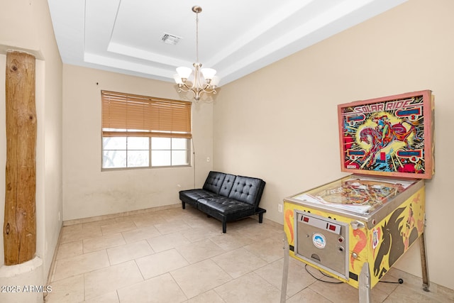 living area with a tray ceiling, visible vents, and a notable chandelier