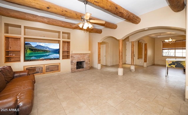 tiled living area featuring arched walkways, beamed ceiling, built in shelves, a fireplace, and ceiling fan with notable chandelier