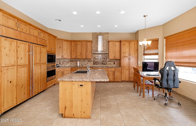 kitchen featuring a notable chandelier, a sink, wall chimney range hood, built in microwave, and oven