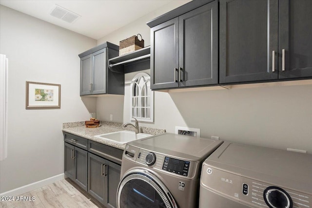 washroom with cabinets, light hardwood / wood-style floors, washer and clothes dryer, and sink