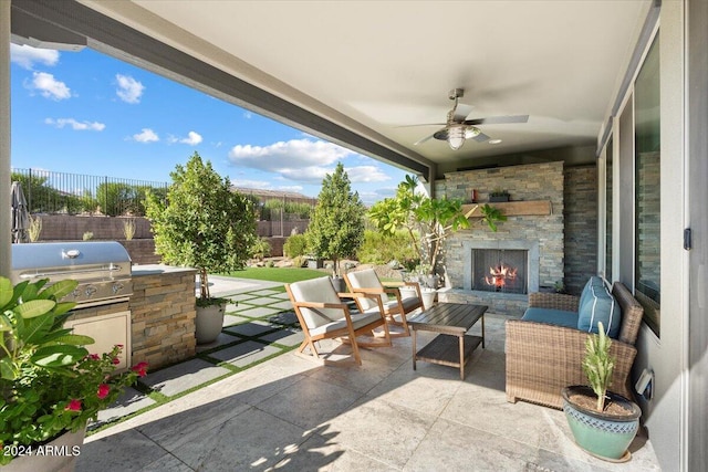 view of patio featuring ceiling fan, area for grilling, and an outdoor stone fireplace