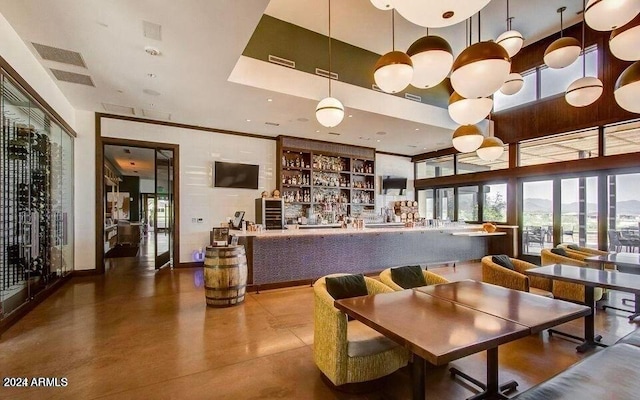 interior space featuring a towering ceiling, concrete floors, and decorative light fixtures