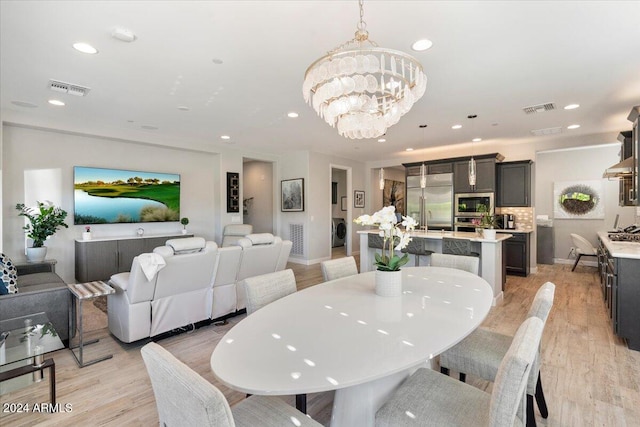 dining area with washer / clothes dryer, a chandelier, and light hardwood / wood-style flooring