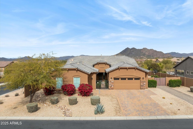 view of front of house featuring a garage, fence, decorative driveway, a mountain view, and stucco siding