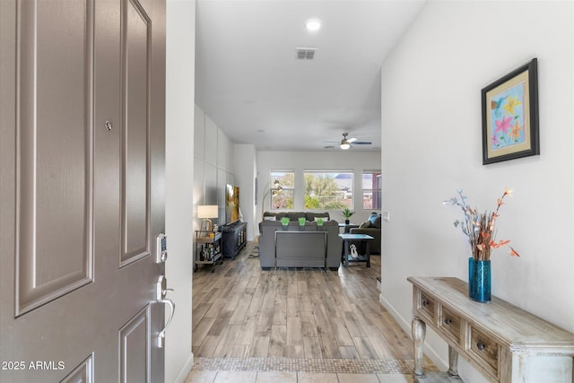 foyer entrance featuring light wood finished floors, ceiling fan, and visible vents