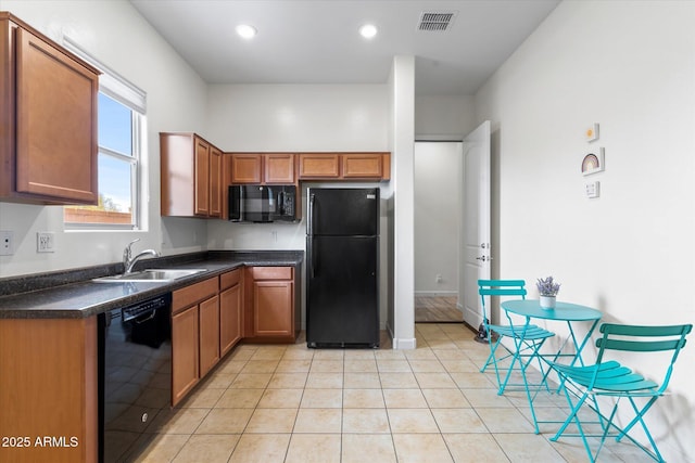 kitchen with light tile patterned floors, a sink, visible vents, black appliances, and dark countertops