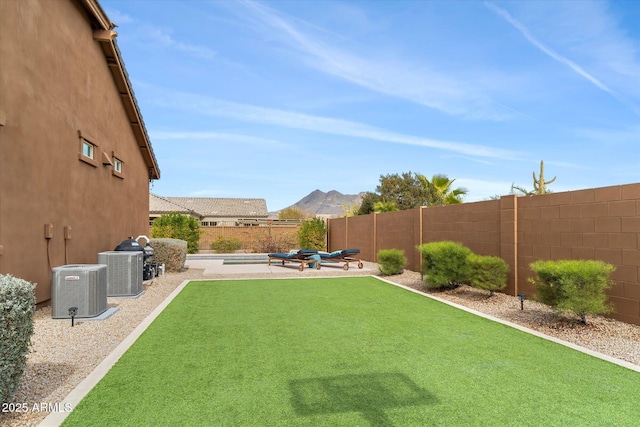 view of yard featuring a patio area, a fenced backyard, a mountain view, and central air condition unit