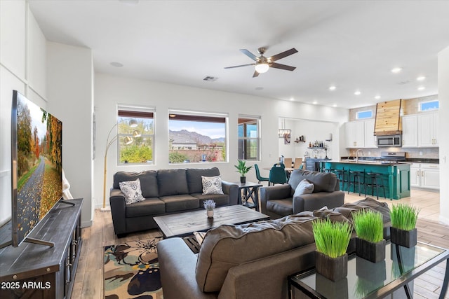 living room featuring a ceiling fan, recessed lighting, visible vents, and light wood finished floors