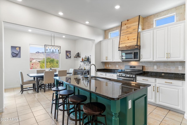 kitchen with stainless steel appliances, light tile patterned flooring, a sink, and white cabinetry