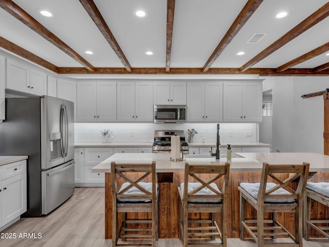 956 S Torrey Pines Dr, Williams, AZ 86046 - kitchen with appliances with stainless steel finishes, light countertops, beamed ceiling, backsplash, and light wood-style floors