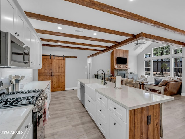 956 S Torrey Pines Dr, Williams, AZ 86046 - kitchen with stainless steel appliances, a barn door, a glass covered fireplace, a ceiling fan, and backsplash