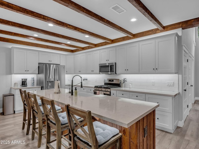 956 S Torrey Pines Dr, Williams, AZ 86046 - kitchen featuring appliances with stainless steel finishes, light wood-style floors, a breakfast bar area, beam ceiling, and backsplash