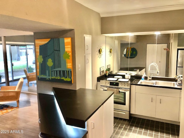 kitchen with a sink, electric stove, dark countertops, white cabinets, and ornamental molding