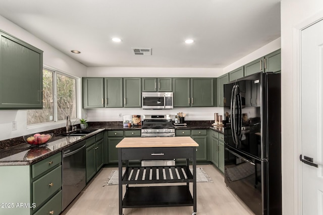 kitchen featuring green cabinetry, stainless steel appliances, visible vents, and a sink