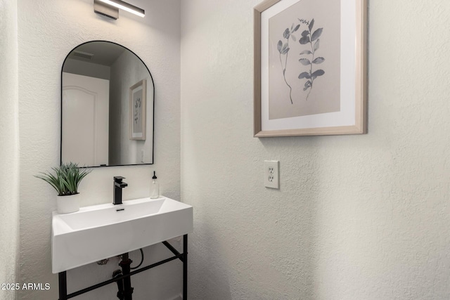 bathroom featuring a sink and a textured wall