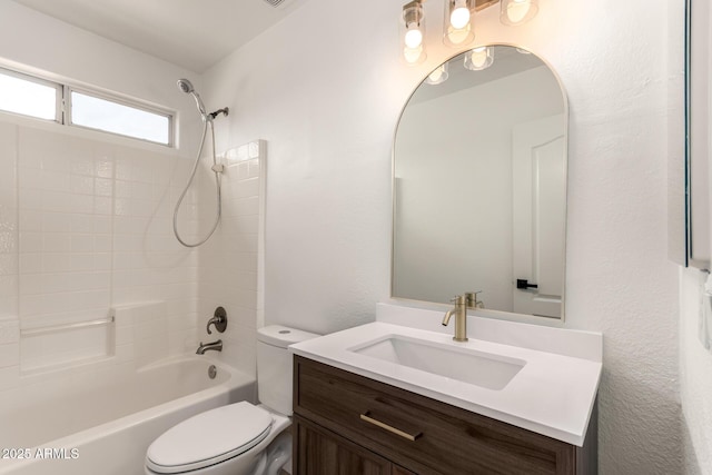 bathroom with vanity, toilet, a textured wall, and shower / washtub combination