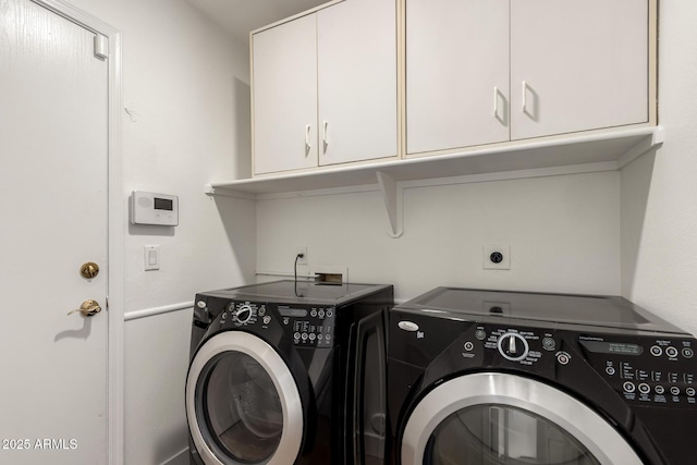 clothes washing area with washer and dryer and cabinet space