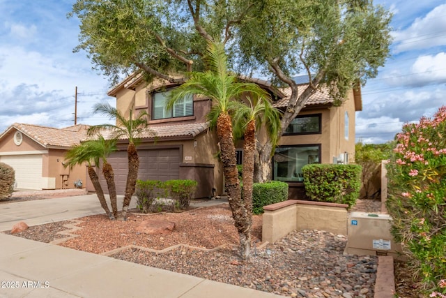 view of front of house with stucco siding, driveway, a tile roof, and an attached garage