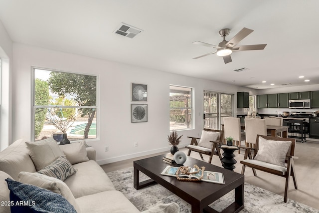 living room with plenty of natural light, visible vents, and ceiling fan