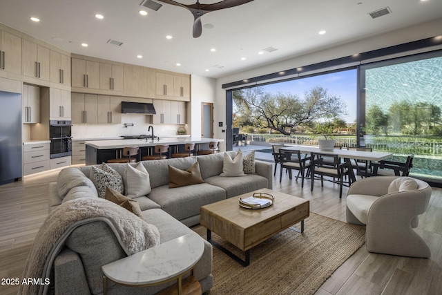 living room featuring ceiling fan, sink, and light hardwood / wood-style floors