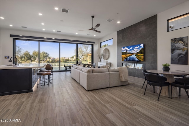 living room featuring wood-type flooring, sink, and ceiling fan