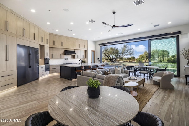 dining space featuring ceiling fan, sink, and light wood-type flooring