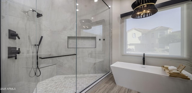 bathroom featuring wood-type flooring, separate shower and tub, and a notable chandelier