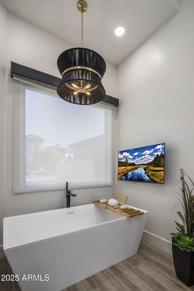 interior space with a bath, hardwood / wood-style flooring, a wealth of natural light, and a chandelier