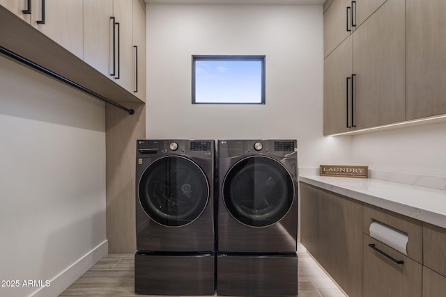 washroom with cabinets, light hardwood / wood-style floors, and washer and dryer