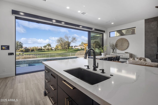 kitchen with light stone counters, sink, and light hardwood / wood-style flooring