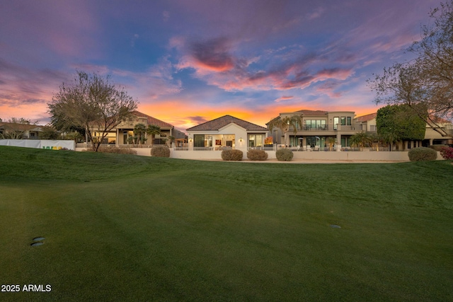 back house at dusk with a lawn