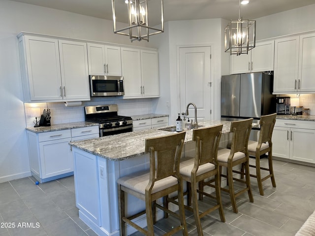 kitchen featuring stainless steel appliances, a center island with sink, and white cabinets