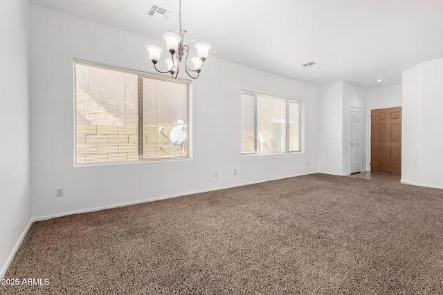 carpeted spare room featuring a chandelier