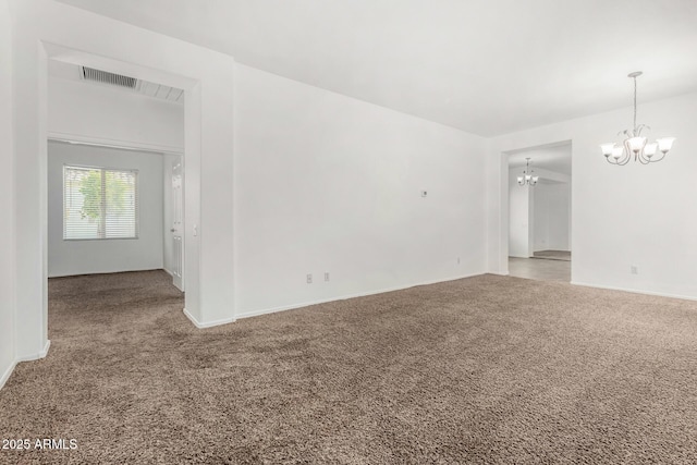 empty room featuring a notable chandelier and carpet