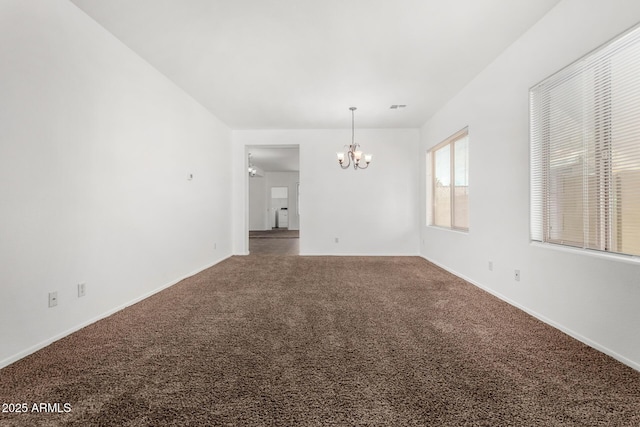 carpeted spare room featuring a chandelier