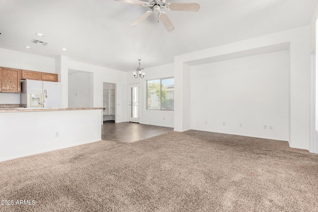 unfurnished living room with ceiling fan with notable chandelier and dark colored carpet