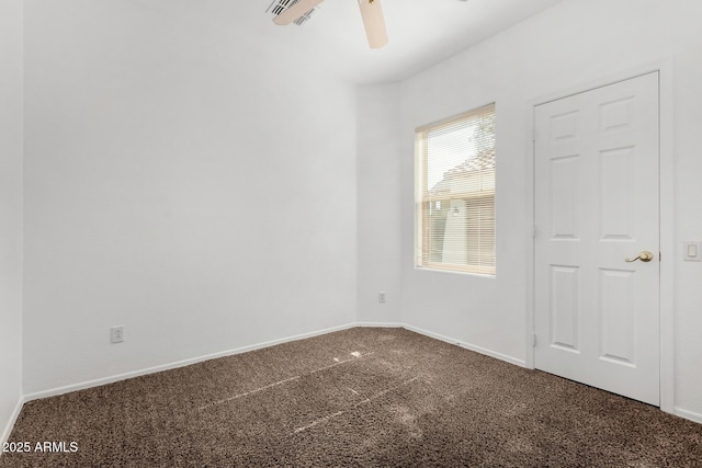 empty room featuring ceiling fan and dark carpet