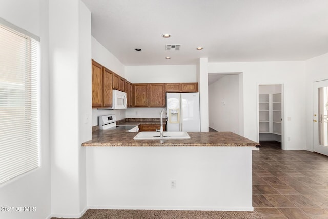 kitchen featuring white appliances, kitchen peninsula, and sink