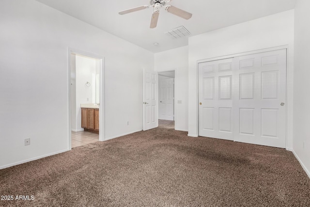 unfurnished bedroom with ensuite bath, light carpet, ceiling fan, and a closet