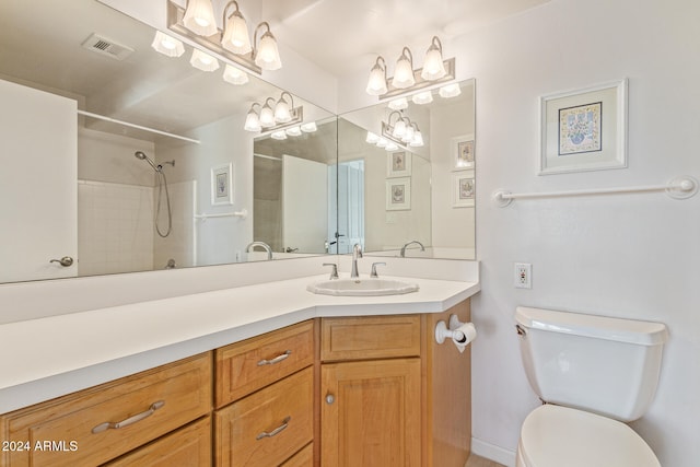 bathroom with vanity, toilet, and tiled shower