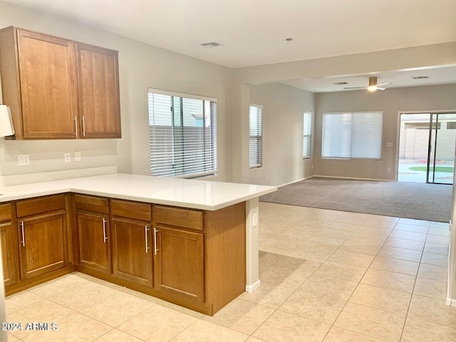 kitchen with light carpet, kitchen peninsula, and ceiling fan