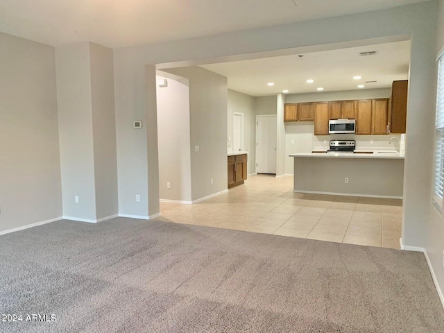 kitchen with sink, appliances with stainless steel finishes, light carpet, and kitchen peninsula