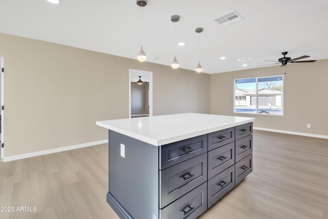 kitchen with ceiling fan, light hardwood / wood-style floors, hanging light fixtures, gray cabinets, and a kitchen island