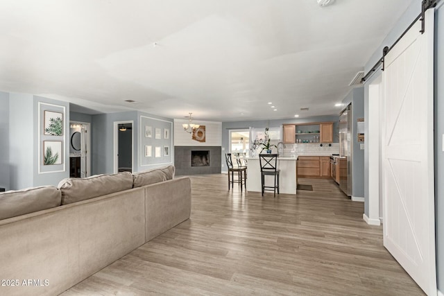 unfurnished living room featuring light hardwood / wood-style floors, sink, a barn door, and a fireplace