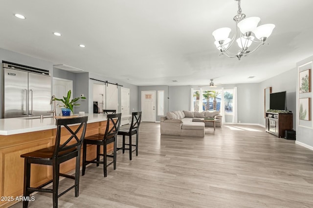 interior space featuring sink, ceiling fan, a barn door, and light hardwood / wood-style floors